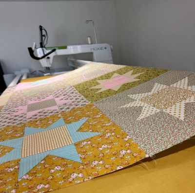 Colorful star-pattern quilt in progress on a sewing machine.