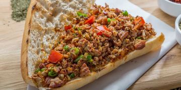 Kıymalı pide üzerinde taze yeşillik ve kırmızı biberler.