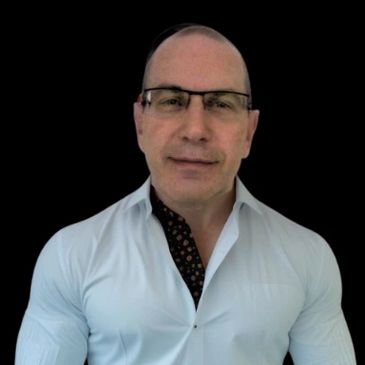 Man with glasses wearing a white shirt against a black backdrop.