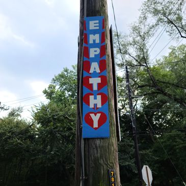 A community sign that reads "EMPATHY" at the corner of Linnean and Nevada Ave.