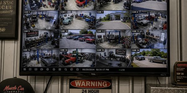 Security monitor showing multiple camera views of a car workshop.