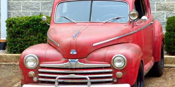 Vintage red car with a classic design parked outdoors.