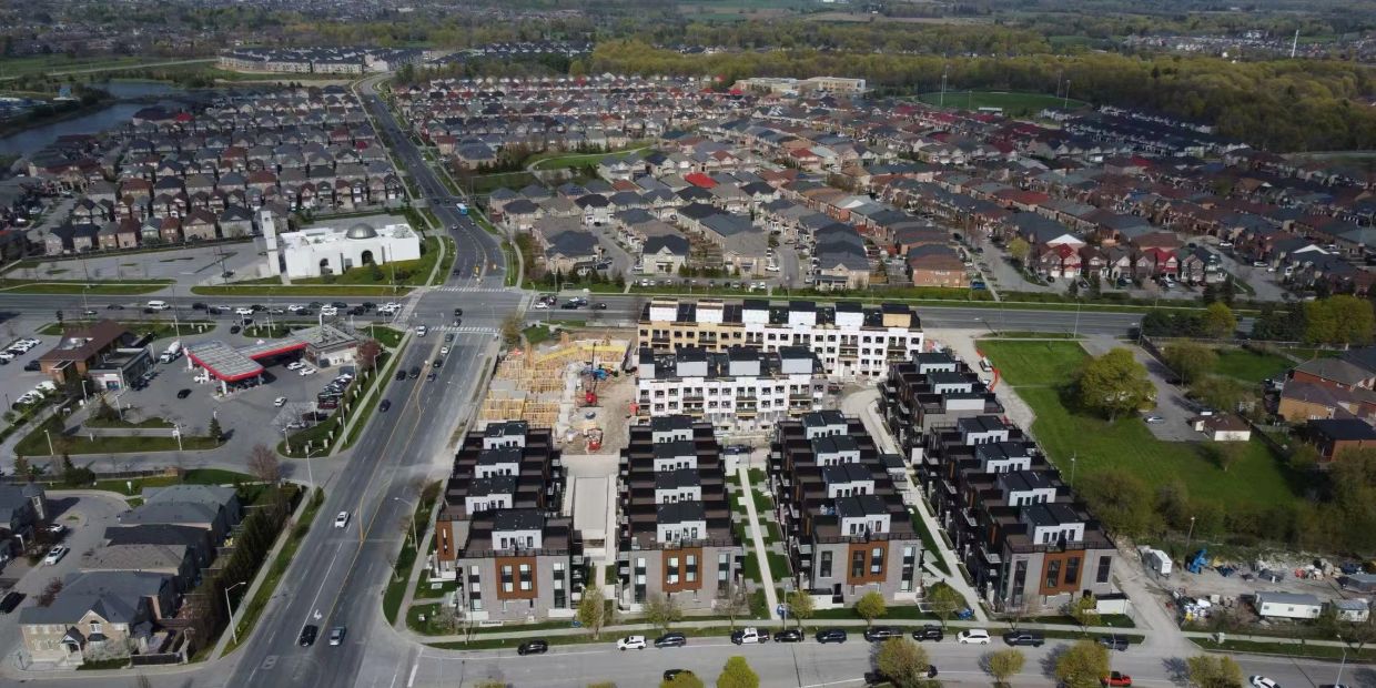 Aerial view of a suburban neighborhood with new housing construction and busy streets.
