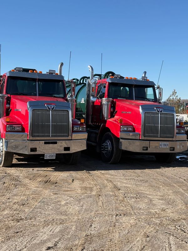 Two red Western Star trucks parked side by side.