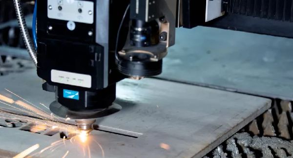 Laser cutting machine slicing through metal sheet with sparks flying.