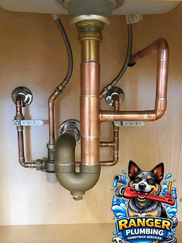 Neatly installed copper plumbing pipes under a sink.