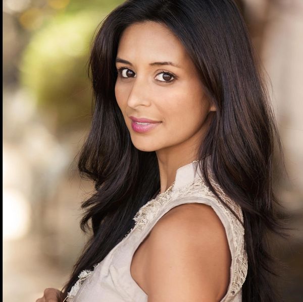 A woman with long dark hair and a soft smile in a sleeveless top.