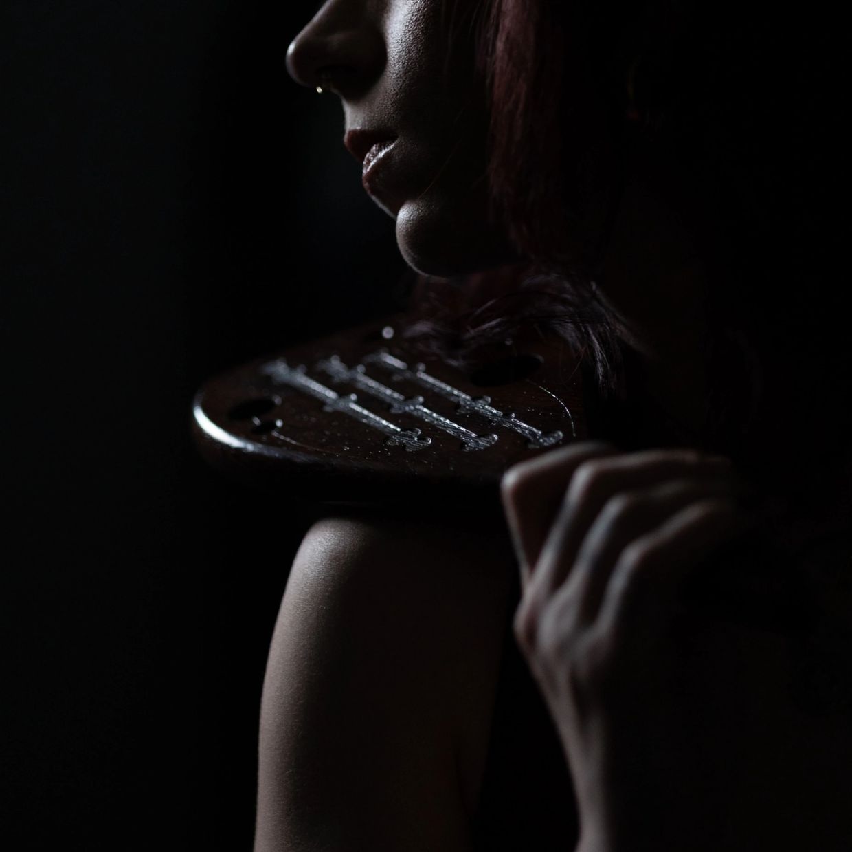 Close-up of woman with violin in dim light.