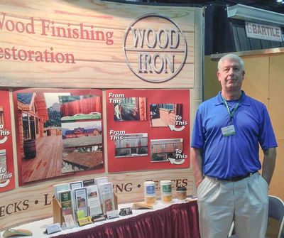 A man stands by a convention center booth full of Wood Iron products.