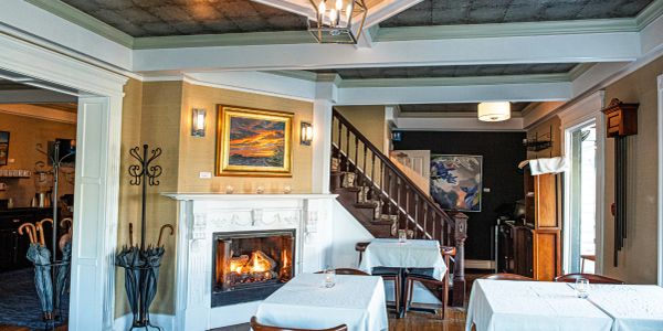 Cozy dining room with fireplace and wooden stairs.