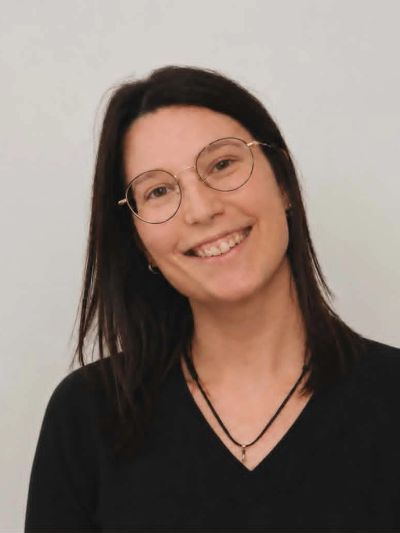 Smiling woman with glasses and dark hair in a black top.