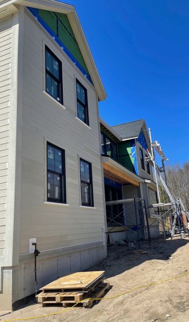 Partially constructed house with scaffolding and building materials outside on a sunny day.