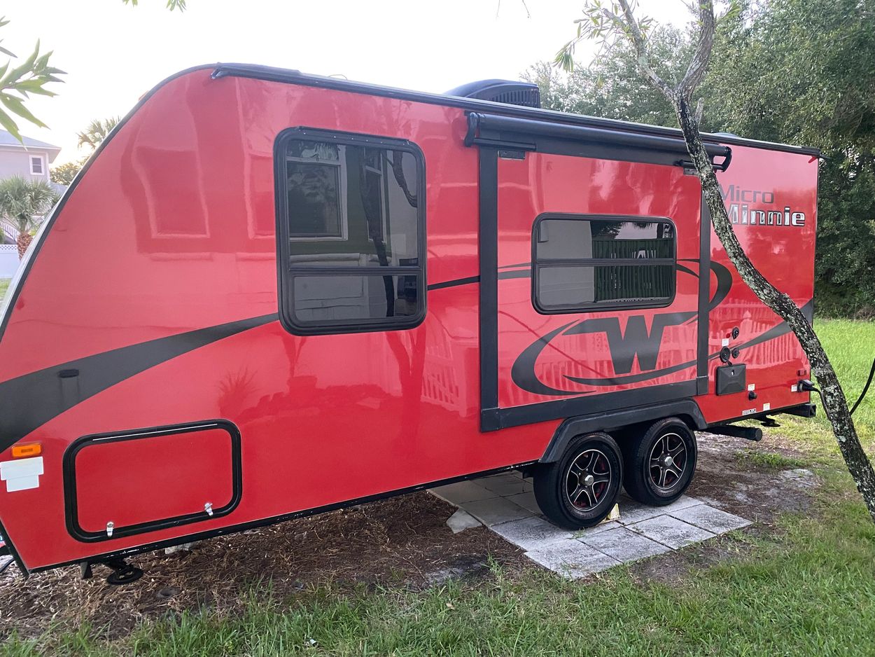 Red Micro Minnie travel trailer parked on grass.