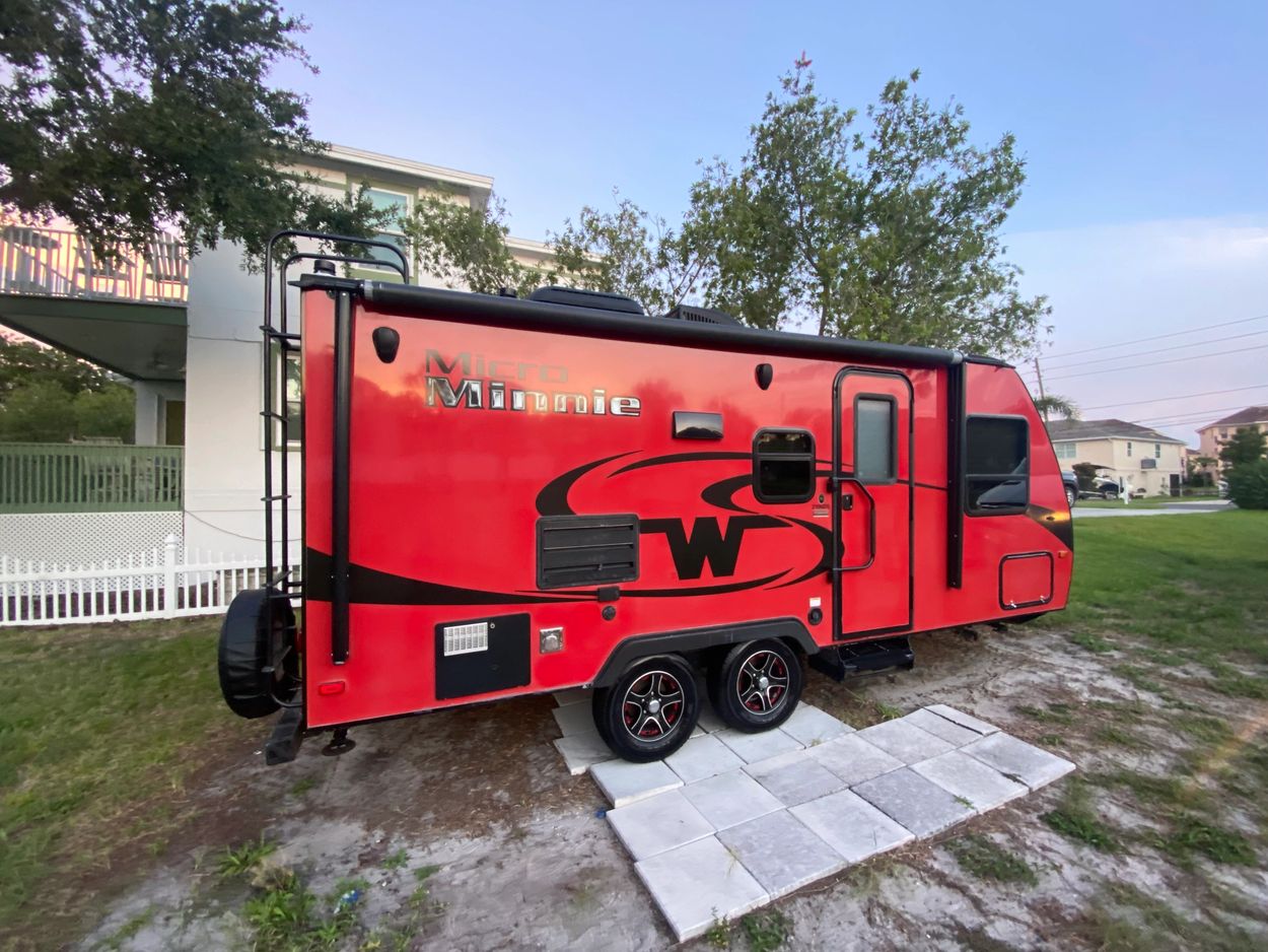 Bright red Micro Minnie trailer parked on grass with nearby houses.