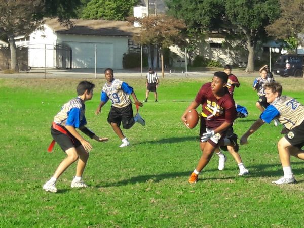 Kids playing flag football on a grassy field.
