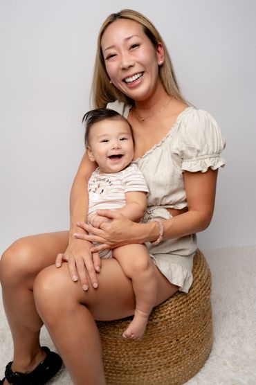 Mom sits holding smiling baby during a studio family photo shoot in Austin, Texas. 