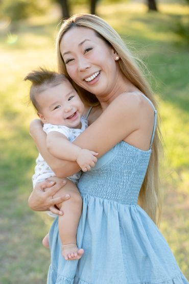 Mom holds smiling baby boy during an outdoor family photography session in Austin, Texas. 