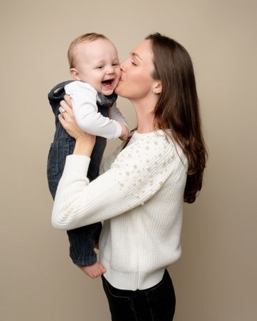 Mom kisses baby during a family photography session in an Austin Photography studio. 