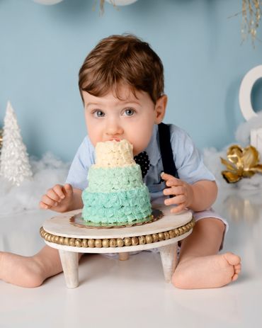 Boy eating cake looking at camera for his first birthday cake smash session in Austin, Texas.