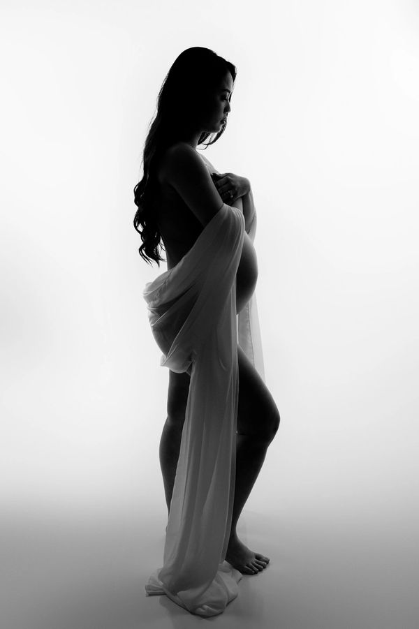 pregnant Mom draped in fabric poses for a maternity photography session in an Austin, Texas studio.