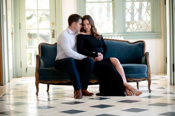 Expecting couple sit on couch during a maternity photoshoot in Austin, Texas.