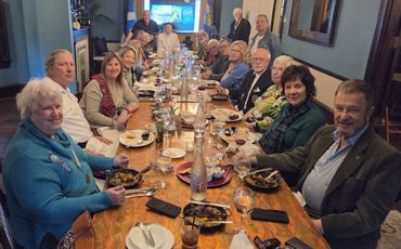 A large group enjoying a meal together around a long wooden table.