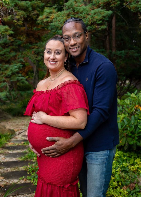 Expecting couple smiling in a garden.