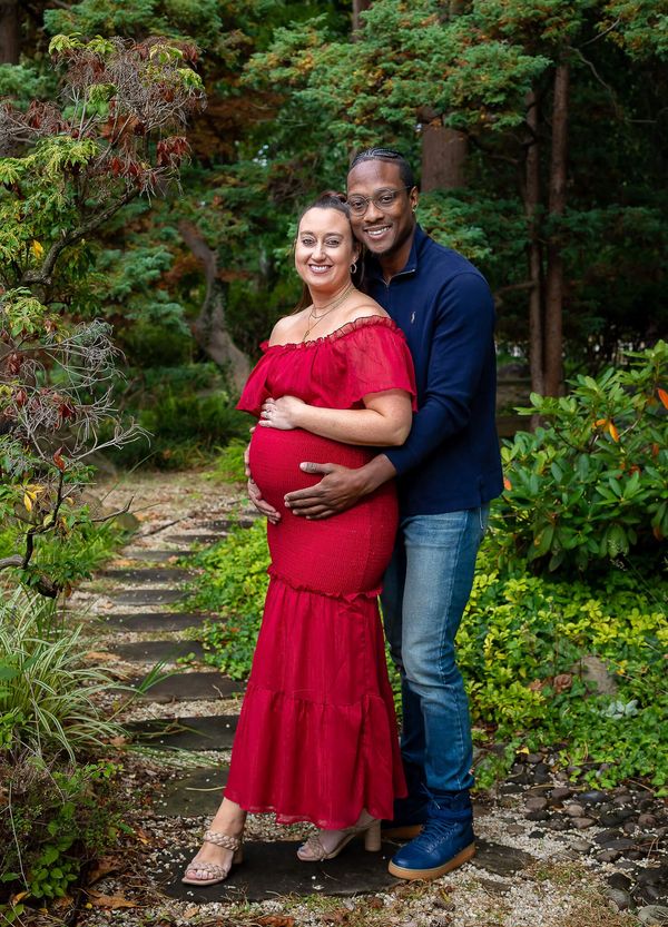 Expecting couple smiling in a garden.