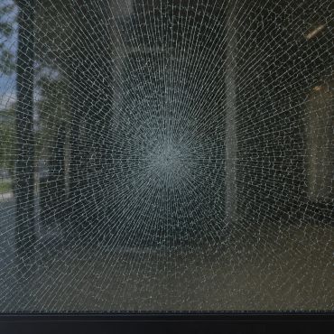 A shattered glass window with a spiderweb crack pattern.