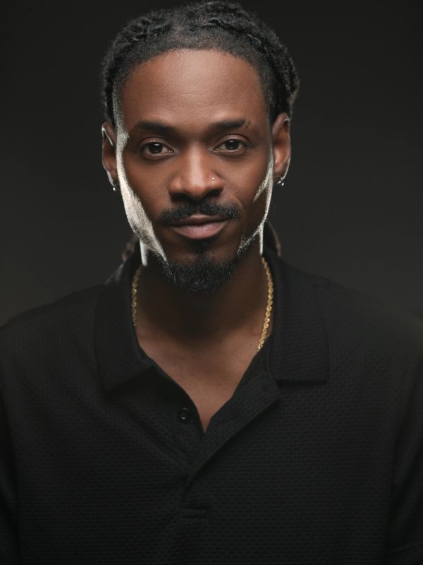 Portrait of a confident man with dreadlocks and facial hair.