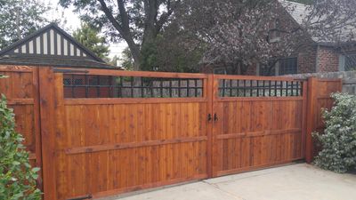 Wooden driveway gate with black metal accents in front of a residential house in Nichols Hills, OK.
