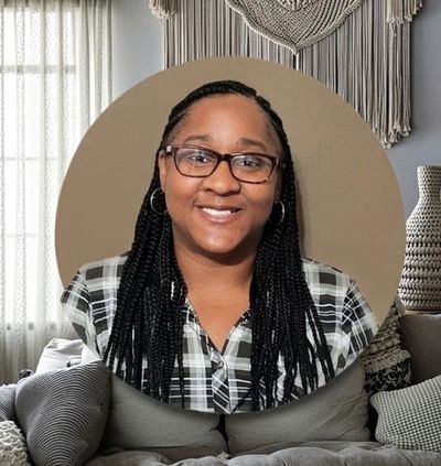 Smiling woman with glasses and braided hair.