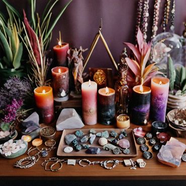 A table full of candles, crystals jewelry and flowers.