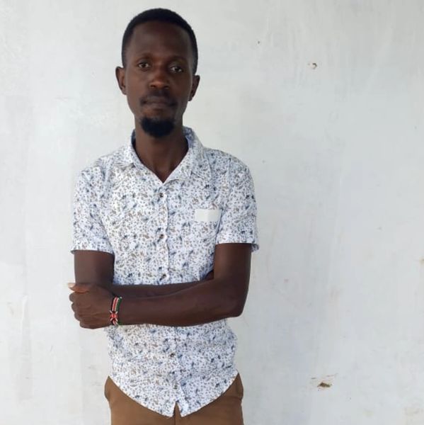 Man standing with arms crossed against a white wall.