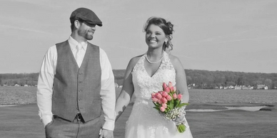 Bride and groom holding hands, bride holding pink tulip bouquet.