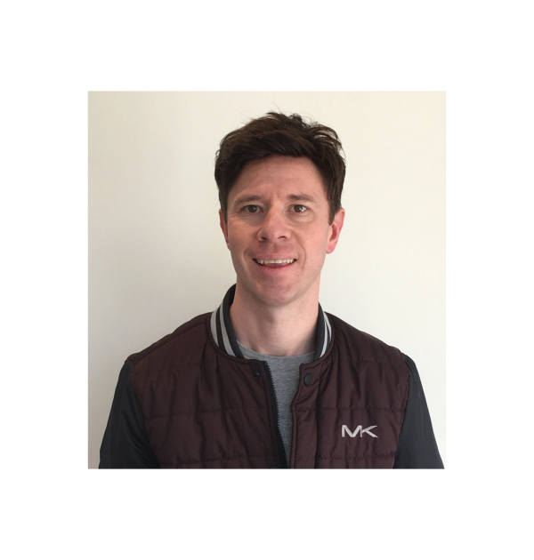 Smiling man wearing a maroon jacket with MK logo.