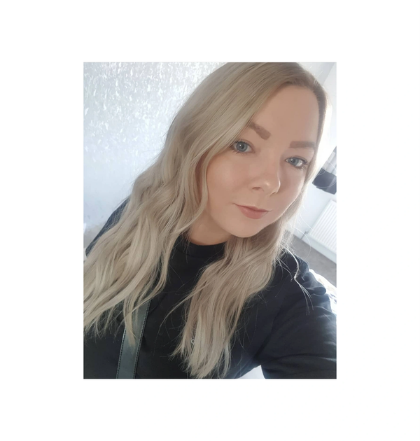Young woman with long blonde hair taking a selfie indoors.
