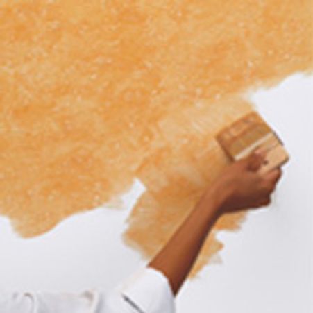 Person applying textured paint on a wall with a brush.