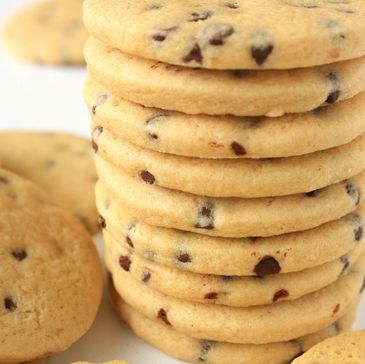 Stack of chocolate chip cookies piled high on a white surface.