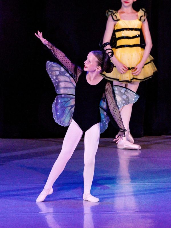 Child dancer dressed as a butterfly, with another in a yellow costume.
