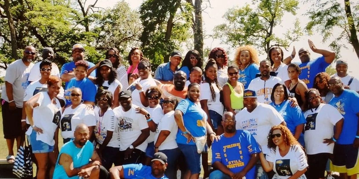 Large group of people posing outdoors on a sunny day.