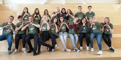 High school students in YSC t-shirts forming hearts with their hands.