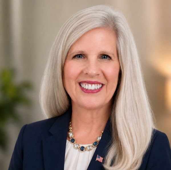 Smiling woman with long silver hair in professional attire.