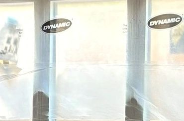 Three window panes covered with protective plastic film labeled "Dynamic".
