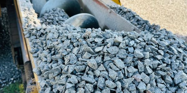 Close-up of crushed stone on a conveyor belt at a quarry or construction site.