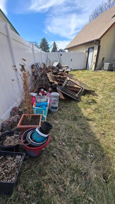 Side view of debris and dismantled materials along the white fence before yard cleanup.