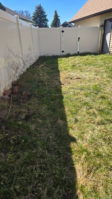 Cleared grass area beside the white fence after yard debris was loaded.