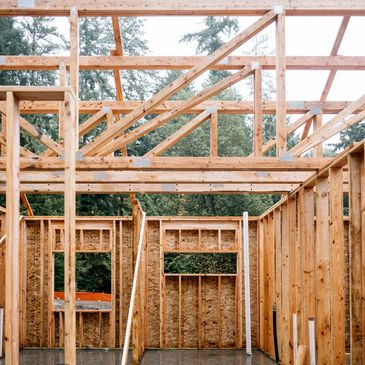 Wooden framing structure of a house under construction in a forested area.