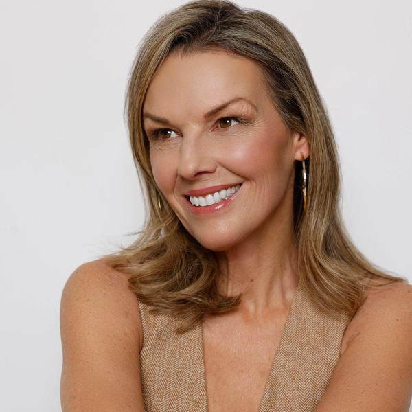 Smiling woman with shoulder-length hair and hoop earrings.