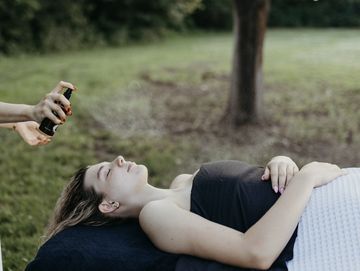 Woman receiving spray treatment on face outdoors.